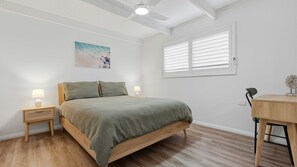 A bedroom with a bed, bedside lamps, a desk, and a ceiling fan. - Amaroo by Book Jervis Bay - Your Premium Coastal Retreat in Jervis Bay - Sanctuary Point (Sanctuary Point)