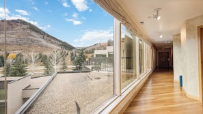 Ein modernes Interieur mit großen Fenstern, Holzboden und Blick auf eine gebirgige Landschaft.
