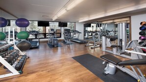 Une salle de sport équipée de machines de cardio, de poids libres et de ballons d’exercice.