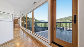 A corridor with large windows leading to a balcony with a view of a mountainous landscape. - Penthouse Luxury • 3BR • Stunning Vail Views (Vail)