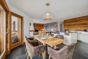 Eine moderne Küche mit Kochinsel, Holzelementen und einem Essbereich mit Holztisch und -stühlen.
