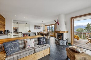 A modern living room with a fireplace, a dining area, and a kitchen. - Welcome to Chalet Infinity by Mrs Miggins, a stunning 140 sqm luxury alpine apartment ideally locate (Crans-Montana)