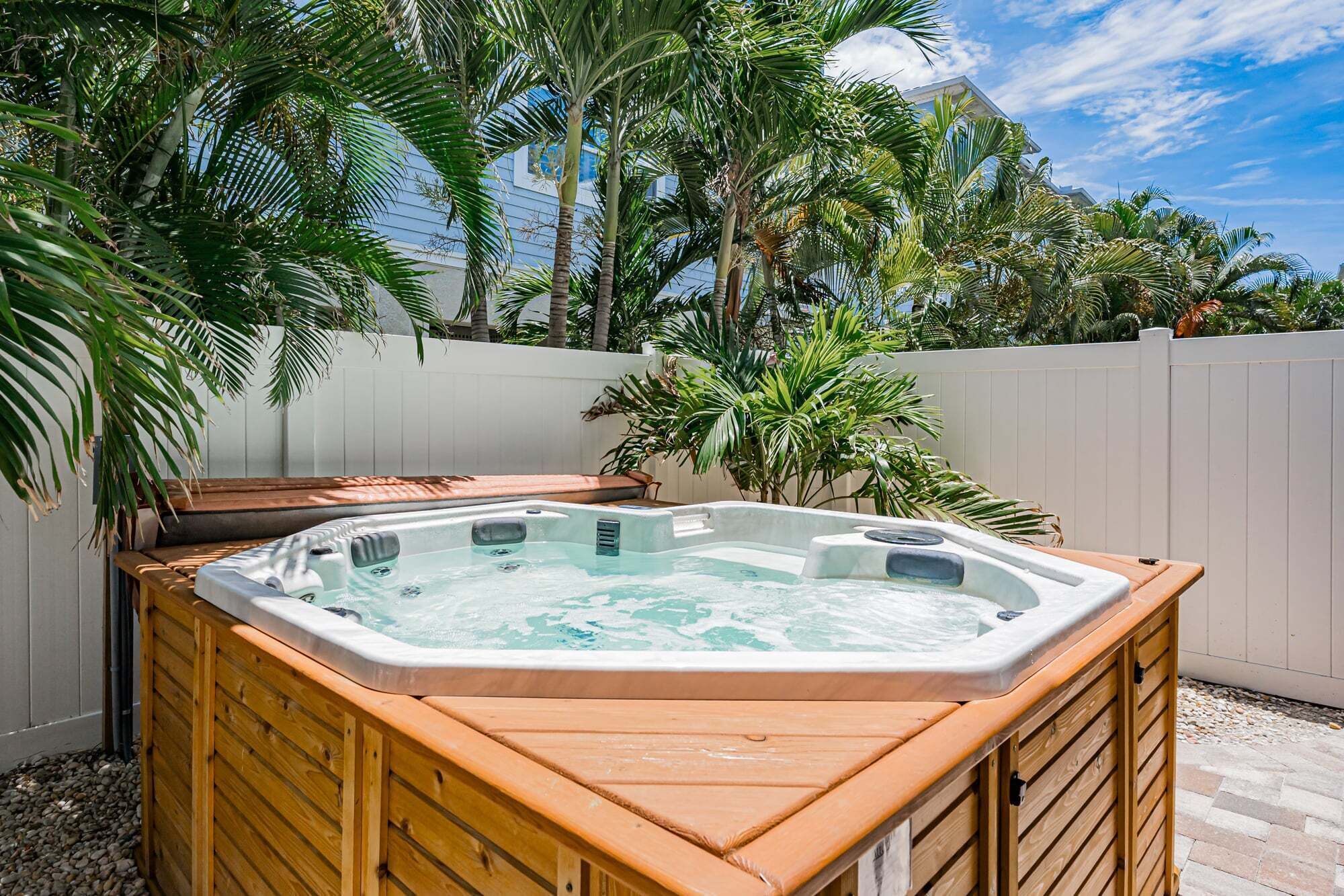 Un jacuzzi dans un jardin, avec une terrasse en bois et des palmiers.