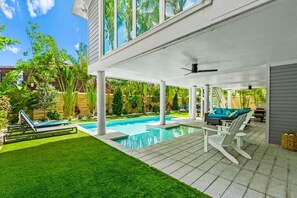 A covered outdoor area with a pool, lounge chairs, and a patio table. - Sunset at 714 - Luxury Island Retreat with Heated Pool Near Bean Point Beach (Anna Maria)