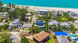A coastal residential area with multiple houses, a beach, and a swimming pool. - Sunset at 714 - Luxury Island Retreat with Heated Pool Near Bean Point Beach (Anna Maria)