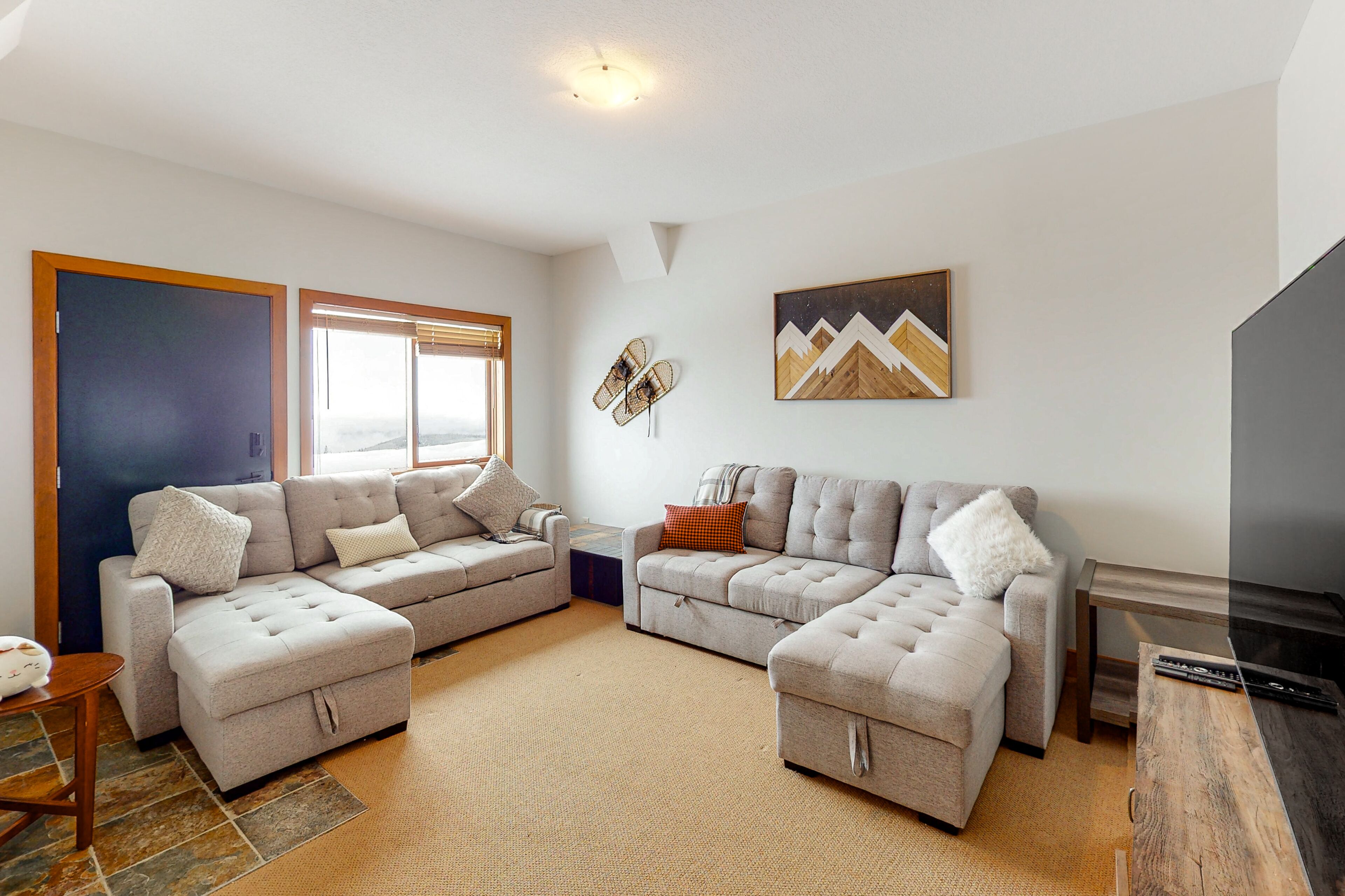 A modern living room with two grey sofas, a coffee table, and a TV stand.