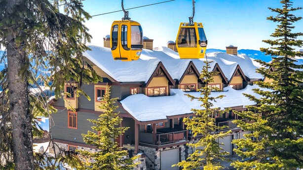 A lodge with a snow-covered roof, wooden exterior, and a ski lift in the background. - Blacksmith Lodge by Okanagan Premier (Beaverdell)