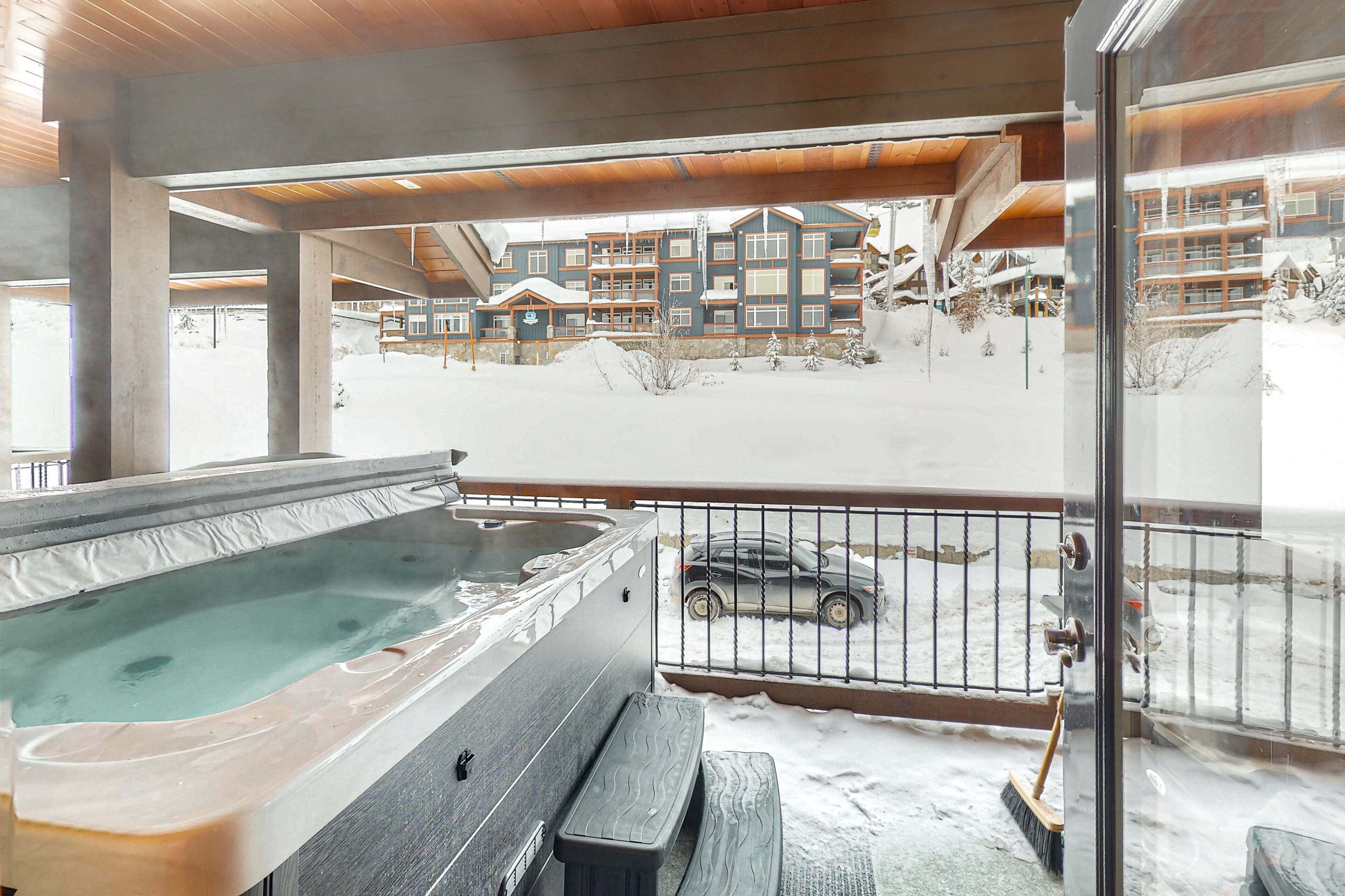 Een jacuzzi op een balkon met uitzicht op een met sneeuw bedekte gebouw.