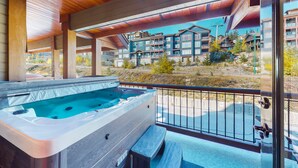 A hot tub under a wooden ceiling with a view of a multi-story building in the background. - Blacksmith Lodge by Okanagan Premier (Beaverdell)