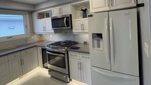A modern kitchen with white cabinets, stainless steel appliances, and a tiled floor.