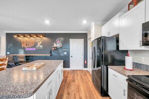 Eine moderne Küche mit Granit-Arbeitsplatten, weißen Schränken, einem schwarzen Kühlschrank und Holzboden.