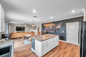 Eine moderne Küche mit weißen Schränken, einer Granit Arbeitsplatte und einem schwarzen Kühlschrank.
