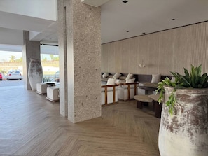 Eine moderne Lobby mit Sitzgelegenheit, großen Pflanzgefäßen und Blick ins Freie.