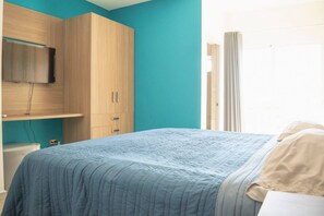 Ein Schlafzimmer mit einem Bett, einem Kleiderschrank und einem an der Wand befestigten Fernseher.