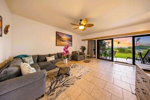 A living room with a sofa, coffee table, and a painting on the wall. - Oceanfront & Oceanview | Pool View | Fully Renovated | Walk to Lydgate Beach (Lihue)