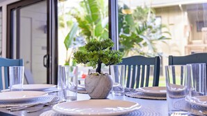 A dining table set with plates, cutlery, and a potted plant. - Oceanfront & Oceanview - Heated Pool - Fully Renovated - Walk to Lydgate Beach (Lihue)