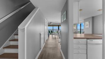 A modern kitchen with white cabinetry, a wooden countertop, and a view to the outside.