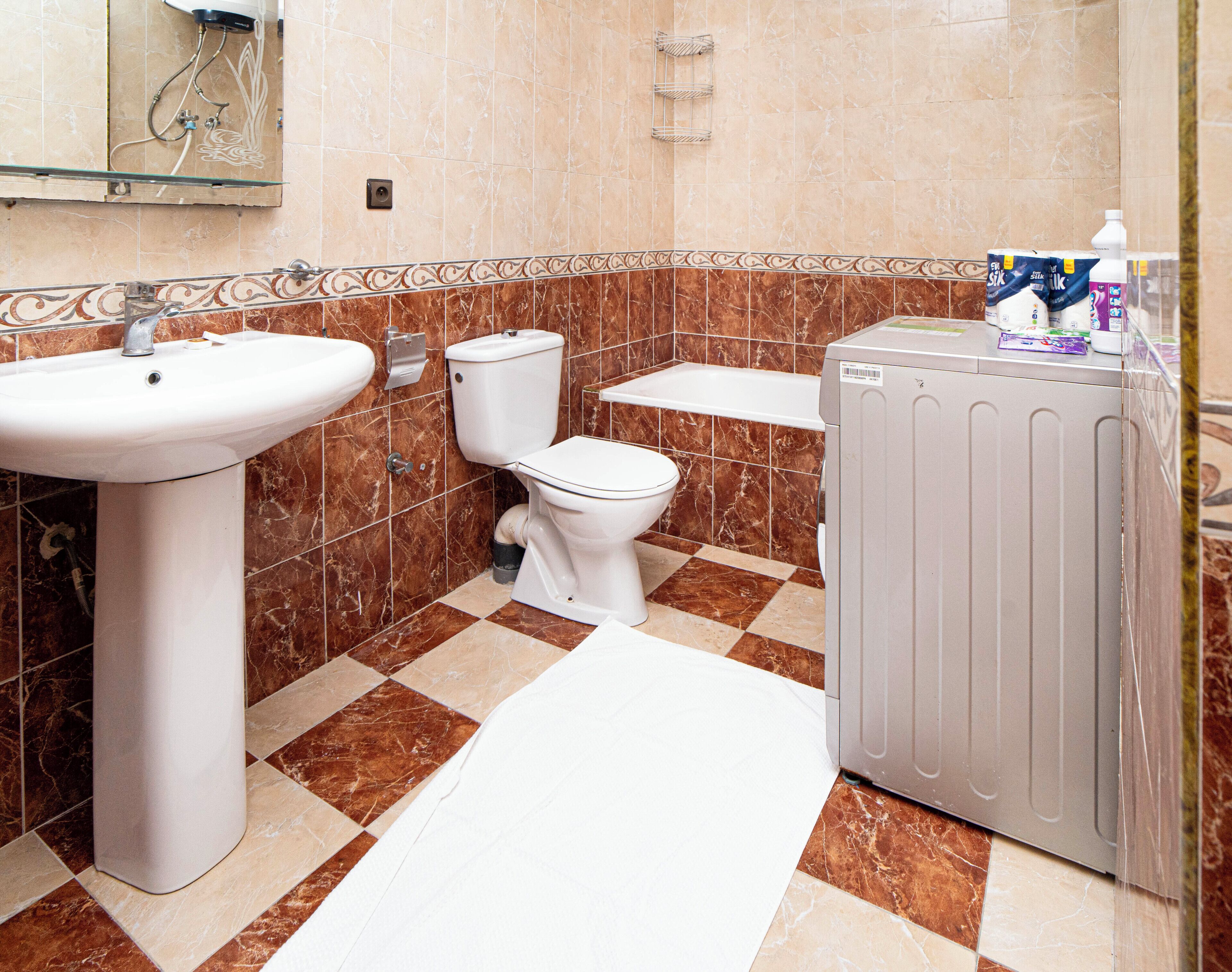 A bathroom with a sink, toilet, and washing machine.