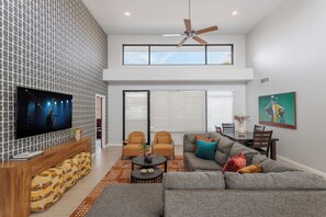 A modern living room with a flat-screen TV, a ceiling fan, and a dining area with a table and chairs. - Lyra - Dual Retreat - In Old Town Scottsdale (Scottsdale)