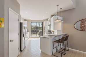 A modern kitchen with a bar area, large windows, and a view of the outdoors. - Lyra - Dual Retreat - In Old Town Scottsdale (Scottsdale)