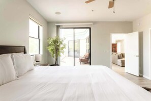 Ein Schlafzimmer mit einem großen Bett, einer Zimmerpflanze und Blick auf einen Balkon.