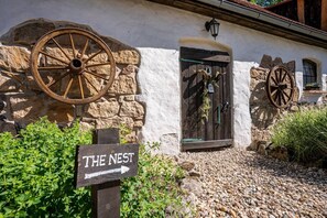 A rustic building with stone walls, wooden wheels, and a sign indicating 'The Nest.'