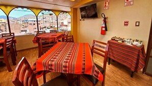 A restaurant with tables covered in patterned tablecloths, a fire extinguisher, and a television on the wall. - PUKANTU  (Puno)