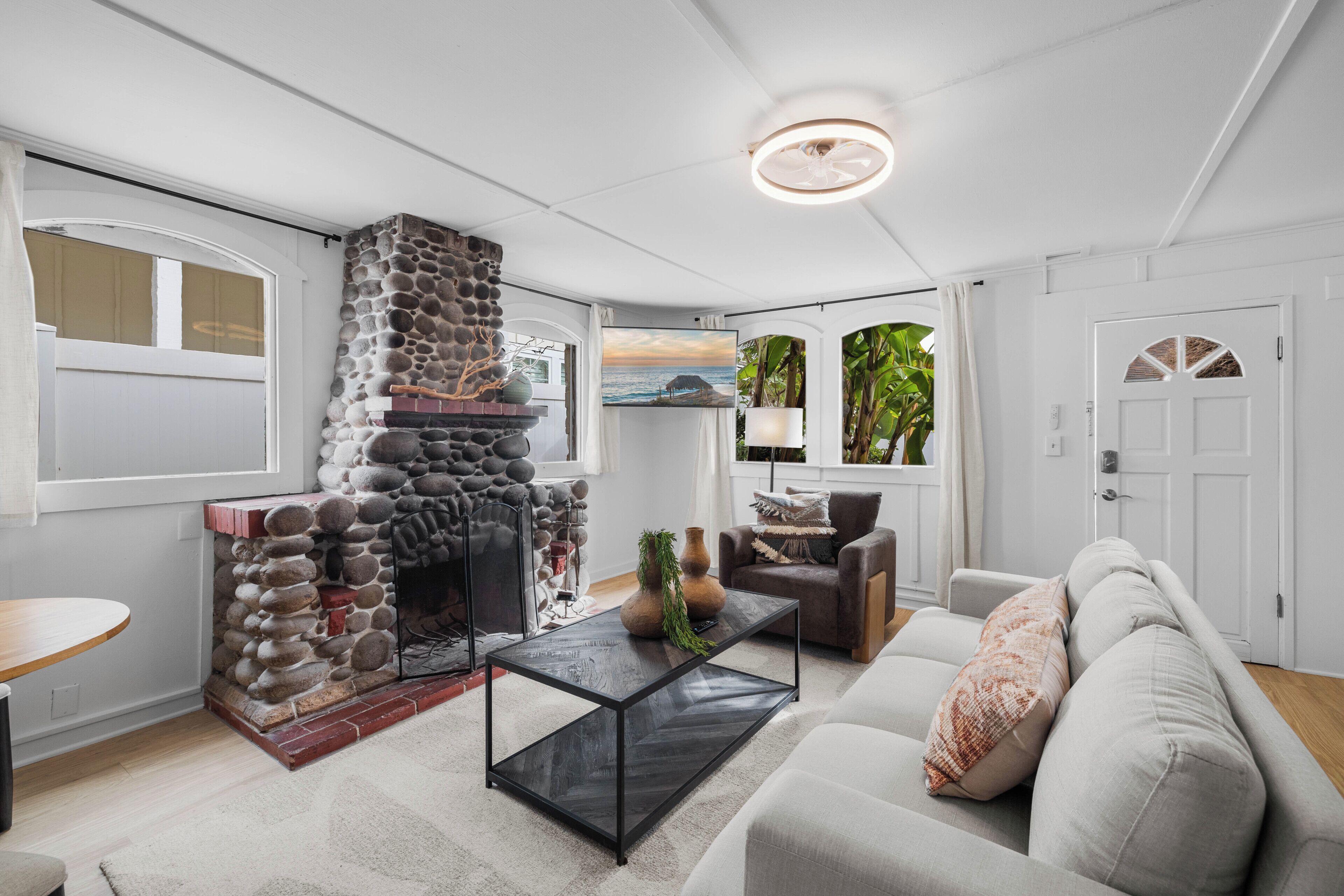 A living room with a stone fireplace, a sofa, a coffee table, and a television.