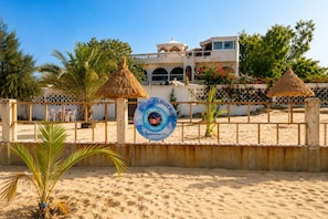 A beachside villa with a signboard, palm trees, and a fence. - Blue Lagoon | Garden Floor (Warang)