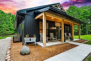 Un chalet moderne doté d’une véranda, de chaises en bois et d’une enseigne indiquant : « Espace de détente ».
