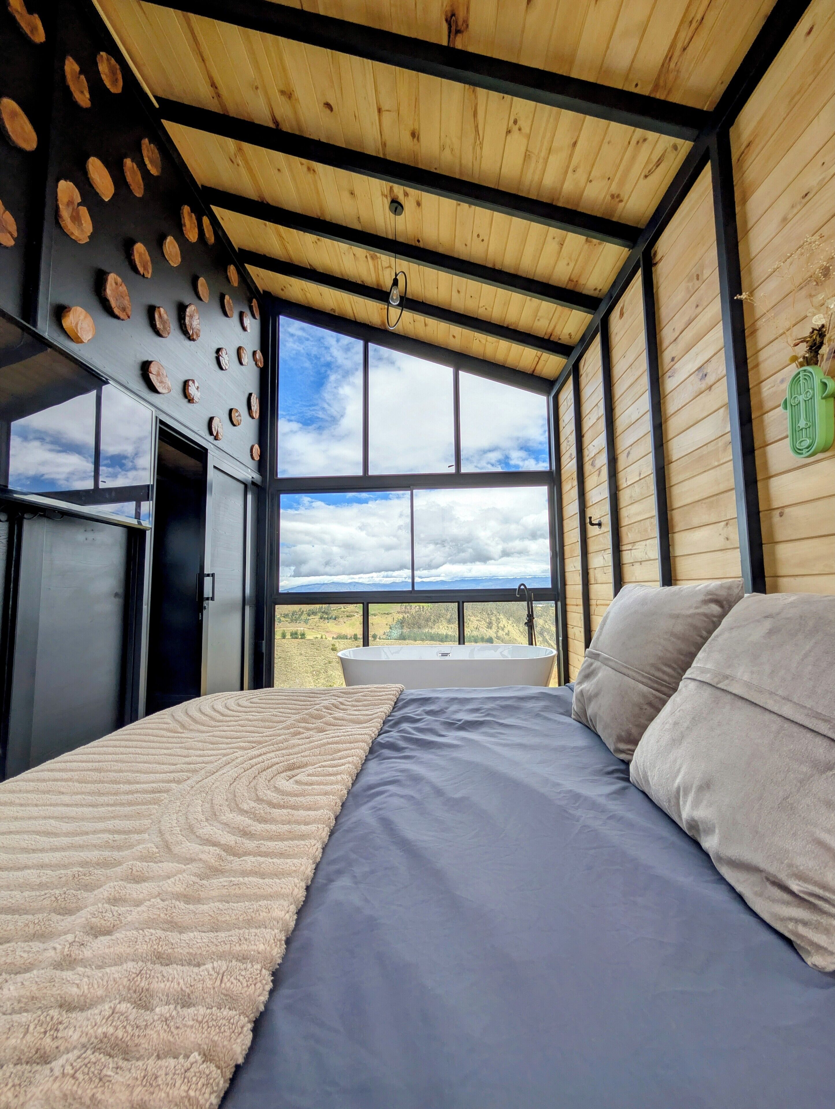 A bedroom with a large bed, a bathtub, and a view of the landscape.