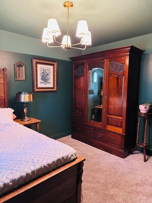 Ein Schlafzimmer mit einem Bett, einem Holzschrank, einem Spiegel und einer Chandelier.