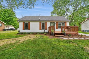 Ein eingeschossiges Haus mit Veranda, Garage und gepflegtem Rasen.