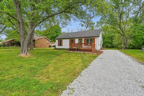 A single-story house with a front porch, a gravel driveway, and a grassy yard. - Vintage-Charm Cottage Near 386, 25 Min to Downtown Nashville (Gallatin)