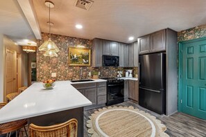 A modern kitchen with a central island, stainless steel appliances, and a decorative backsplash. - Vintage-Charm Cottage Near 386, 25 Min to Downtown Nashville (Gallatin)