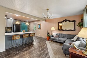 Une cuisine moderne dotée d’un îlot central, de tabourets de bar et d’un coin repas comprenant un canapé et une lampe.
