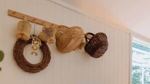 Um quarto com um painel de parede tecido, uma cesta de vime e uma coroa de vime.