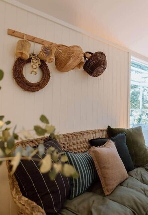 Una habitación con un tapiz de pared tejido, una cesta de mimbre y una corona de fibras naturales.