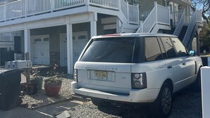 A two-story house with a white exterior, a balcony, and a driveway. - Highlands cottage across the street from Proving Ground and Twin Lights Marina (Highlands)