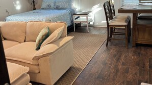 A bedroom with a bed, a sofa, a dining table, and a chair. - Highlands cottage across the street from Proving Ground and Twin Lights Marina (Highlands)