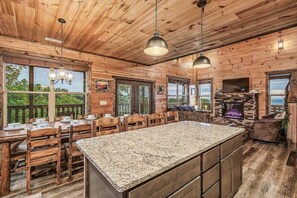 Ein Holzblockhaus-Interieur mit Kücheninsel, Essbereich und Kamin.