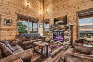 Ein rustikales Holzhaus-Interieur mit Kamin, Ledersofas und großen Fenstern.