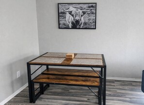 Ein Zimmer mit einem Tisch aus Metall, einem gerahmten Bild an der Wand und Holzboden.
