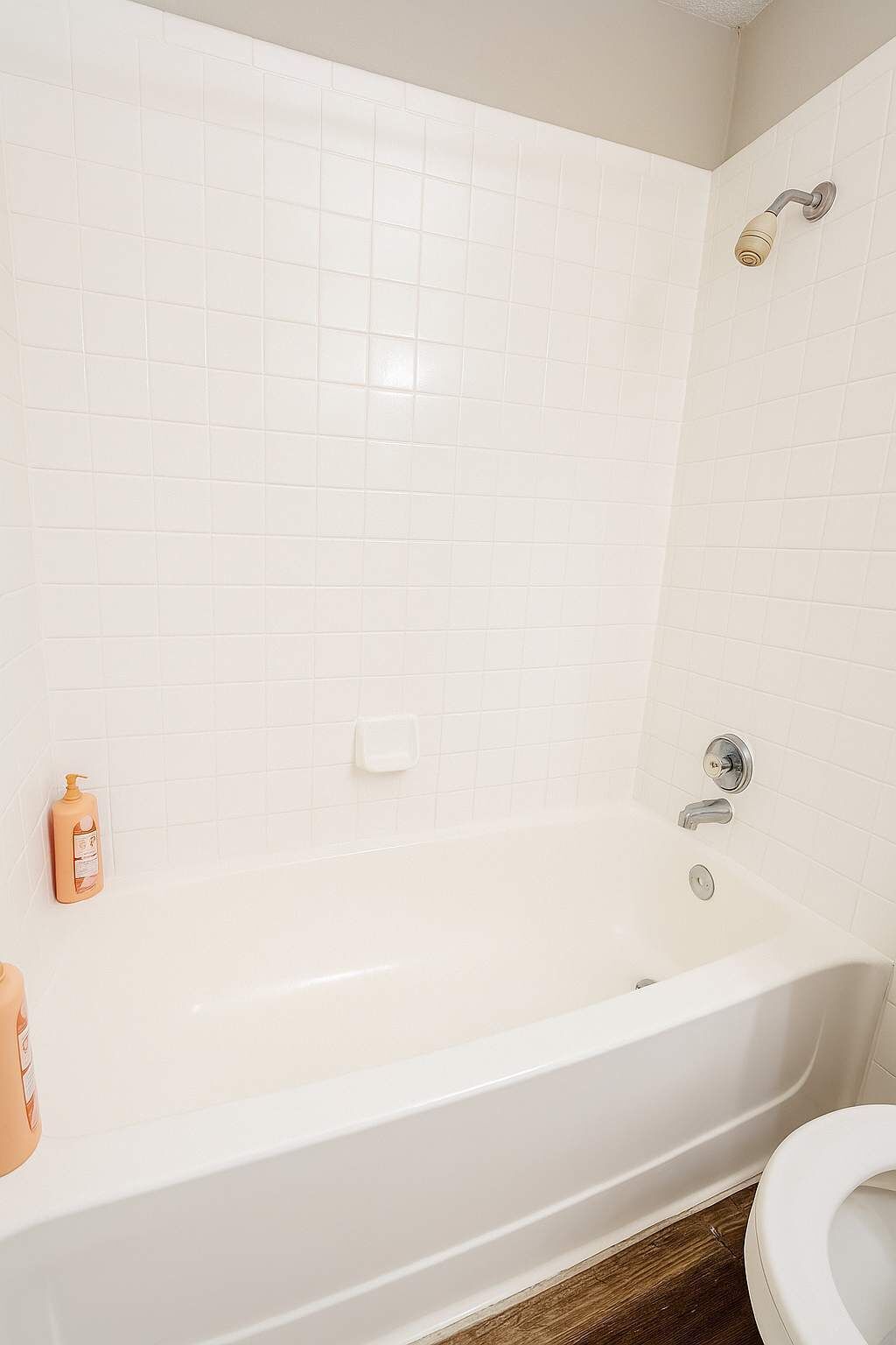 A bathroom with a white bathtub, a toilet, and a showerhead.