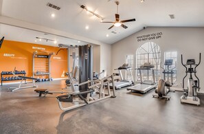 Ein Fitnessstudio mit Trainingsgeräten, motivierenden Sprüchen an der Wand und einem Deckenventilator.