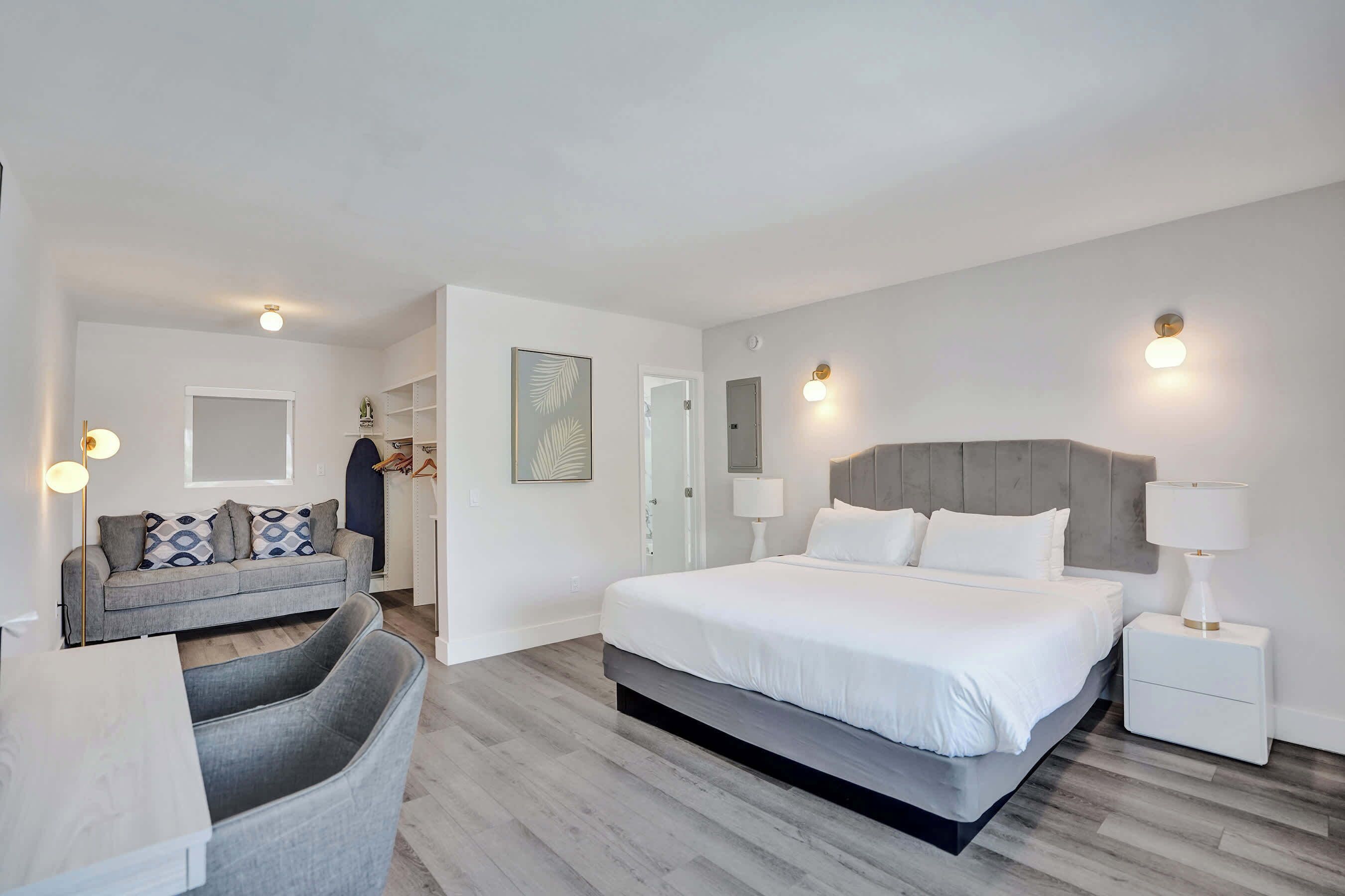 Une chambre moderne avec un grand lit, des tables de chevet, un canapé et un coin repas.