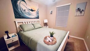 Une chambre à coucher avec un lit, une table de chevet, une lampe et une œuvre d’art.