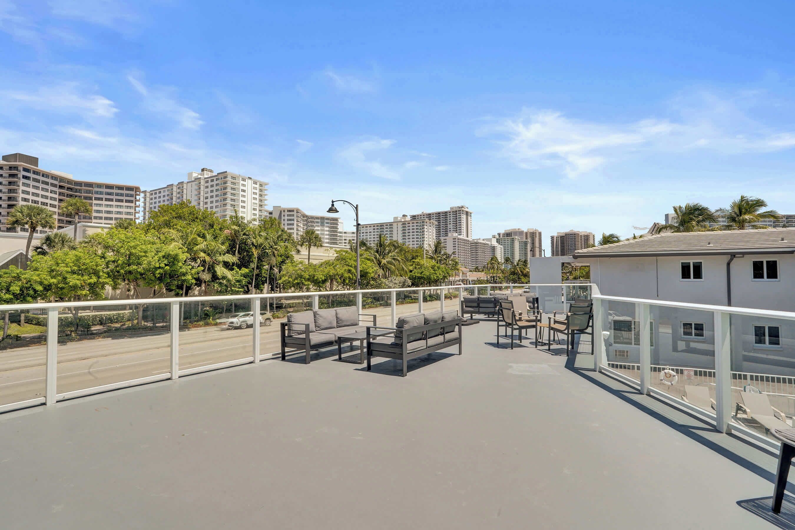 A rooftop terrace with outdoor seating, a view of the cityscape, and a clear sky.