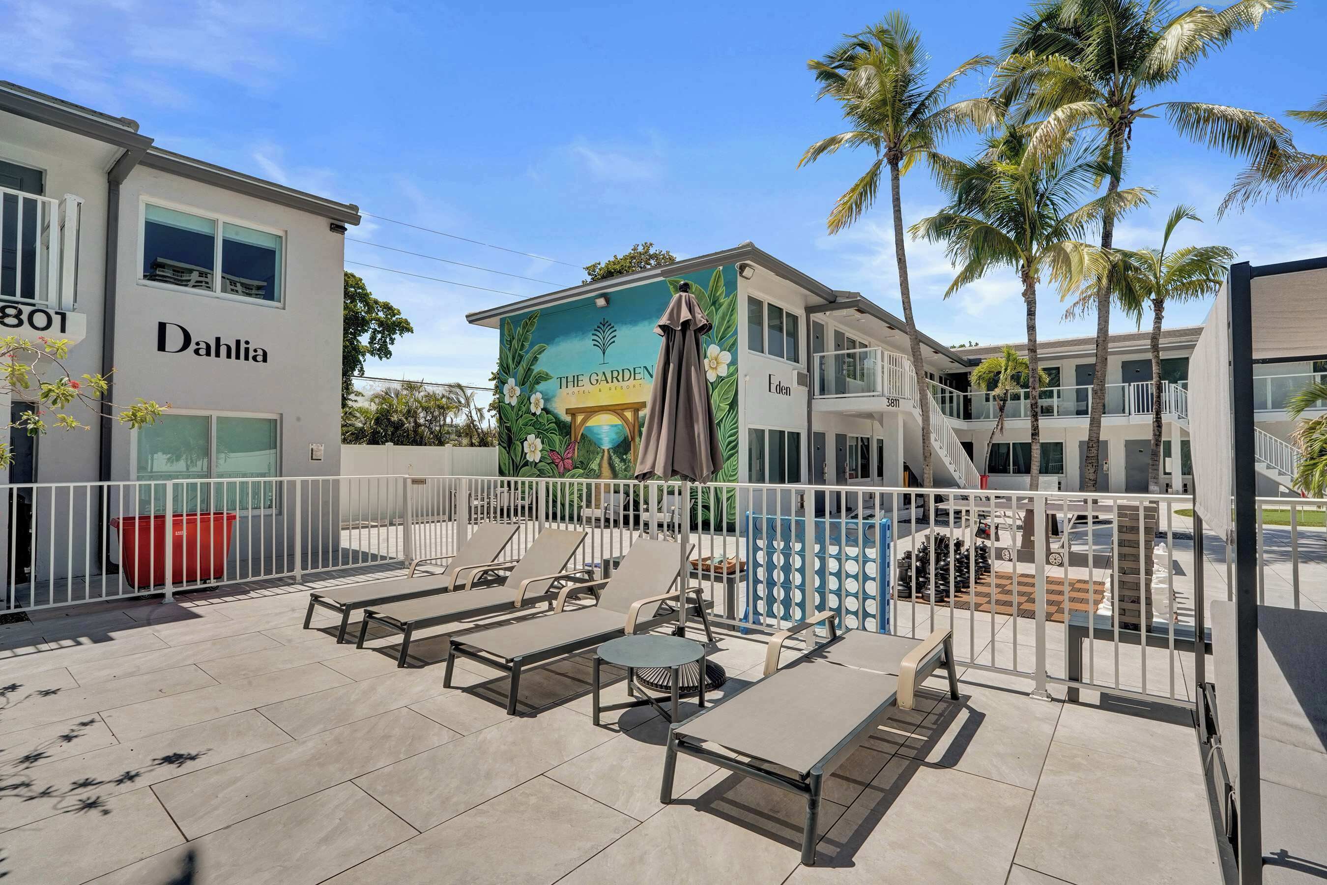 Hotel con terraza al aire libre, palmeras y un mural de un jardín.