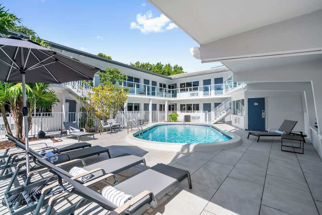A modern building with a swimming pool, outdoor seating, and a covered area.